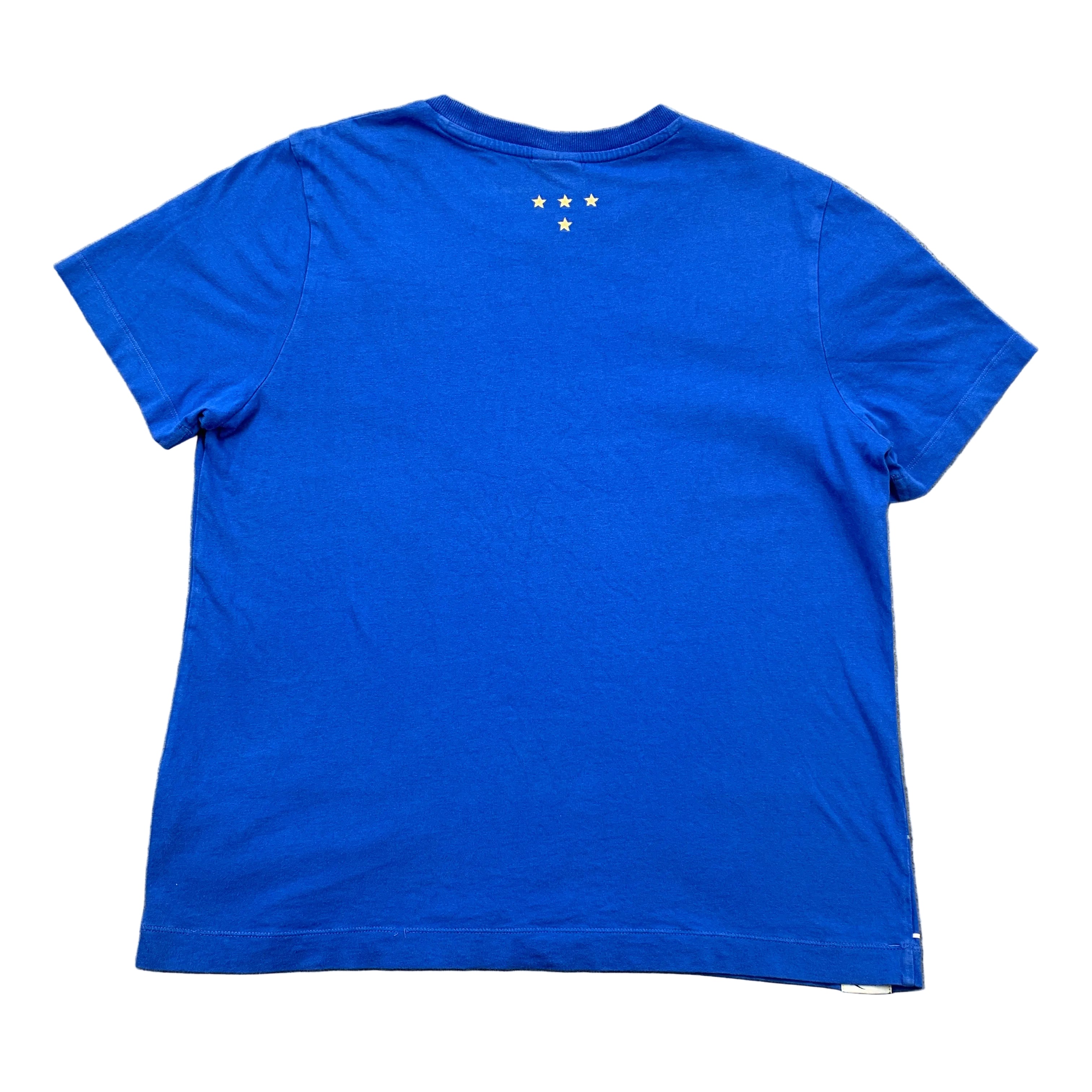 Blue t-shirt with a small logo on the back, laid flat on a gray surface.